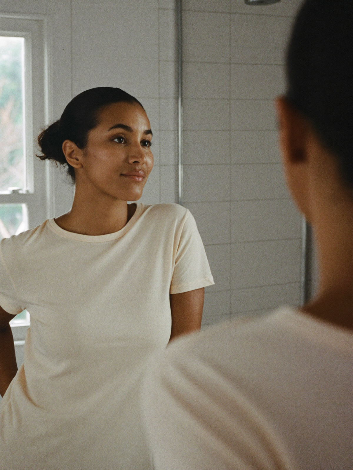Woman at her bathroom mirror in morning light