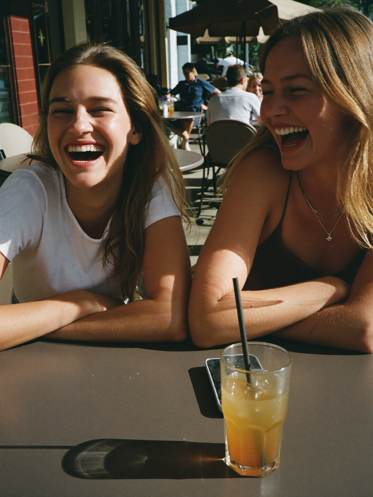 Two friends laughing in short sleeves at a summer cafe